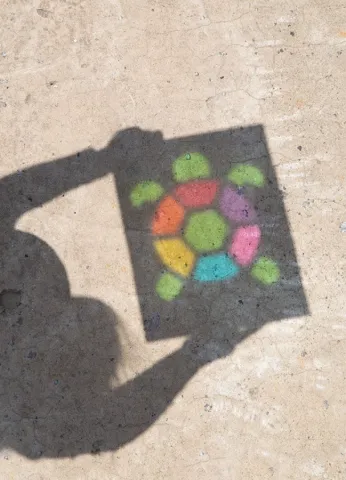 Shadow of a cellophane turtle casted onto the ground.